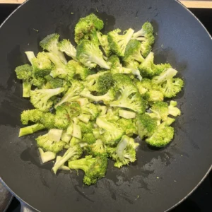 Grüne Brokkoliröschen werden in einer Pfanne angebraten.