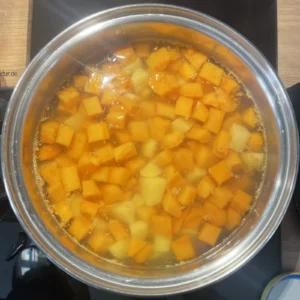 Kartoffel- und Süßkartoffelstücke kochen in einem Topf mit Wasser.