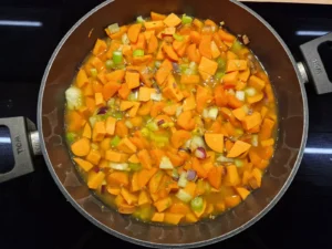 Karotten, Süßkartoffeln und weiteres Gemüse köcheln im Topf.