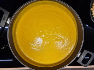 Fein pürierte orangefarbene Karottensuppe im Topf.
